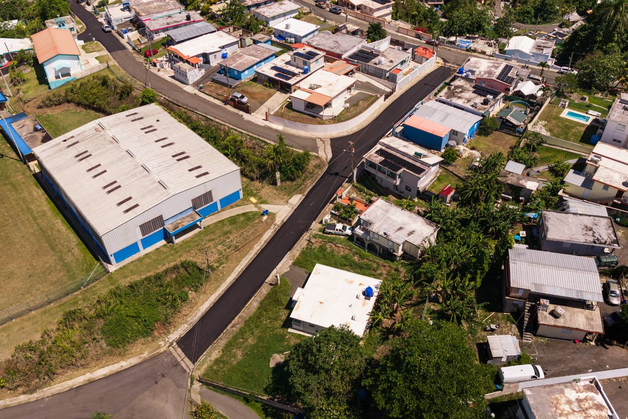 Vista aérea de camino repavimentado junto a estructura comunitaria